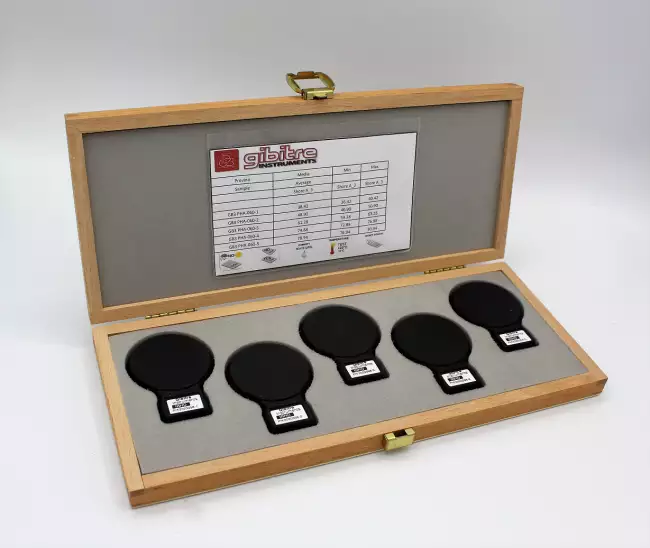 : ショア硬さ試験機およびIDHD硬さ試験機の定期試験用認定試験片。5個の試験片が入った木箱の全景。